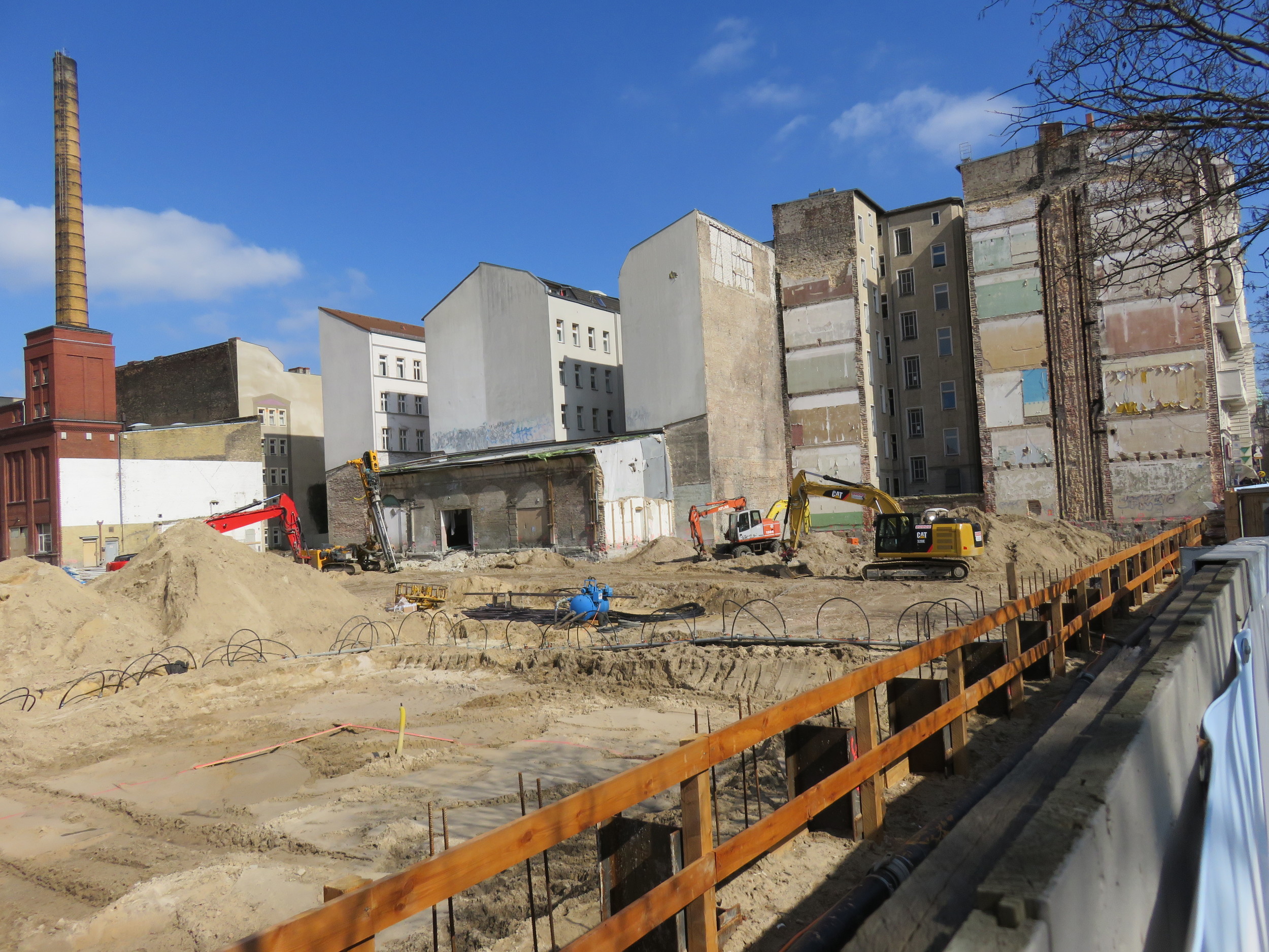 The current construction site, with the brick buildings and smokestack of the former Schultheiss Brewery on the left.