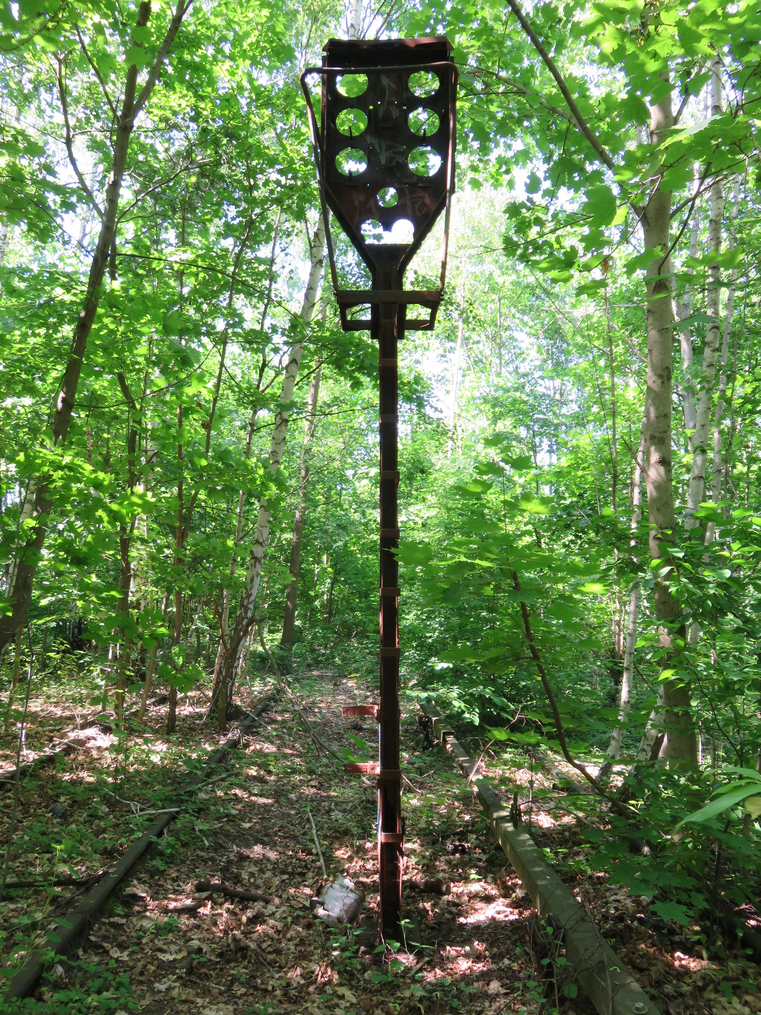 A former signal post on the tracks between Siemensstadt and Gartenfeld stations, now rusted and surrounded by trees.